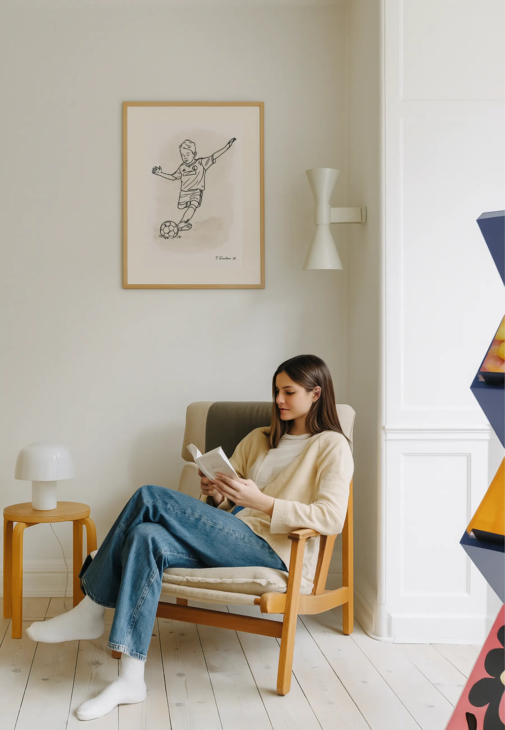 Woman reading a book in a cozy living room with a framed picture on the wall.