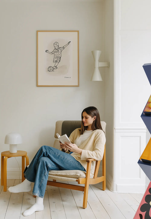 Woman reading a book in a cozy living room with a framed picture on the wall.